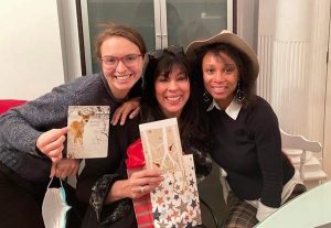 Catherine Dagenais-Savard, Katherine Adams et Kattia Thony sourient avec des cartes de Noël
